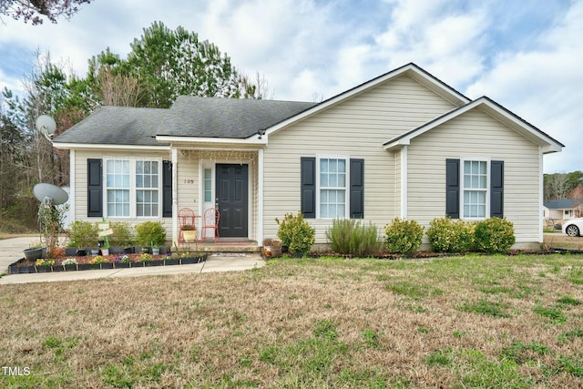 ranch-style home featuring a shingled roof and a front lawn