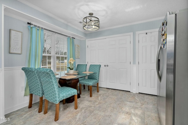 dining room with a wainscoted wall, crown molding, and an inviting chandelier