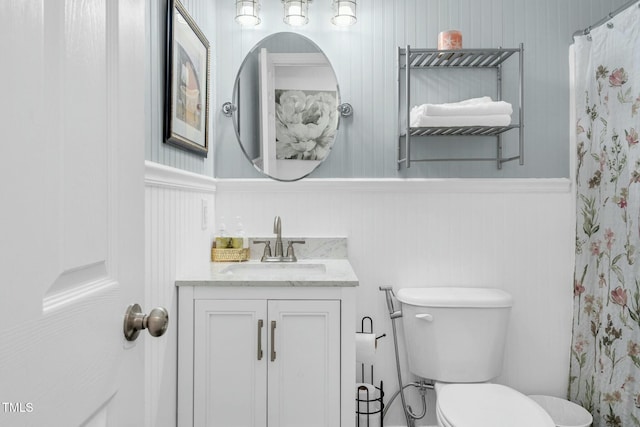 bathroom featuring toilet, wainscoting, a shower with curtain, and vanity