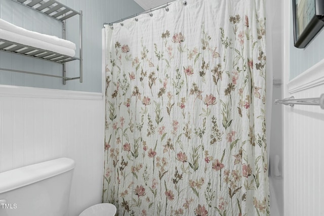 bathroom featuring toilet and a wainscoted wall