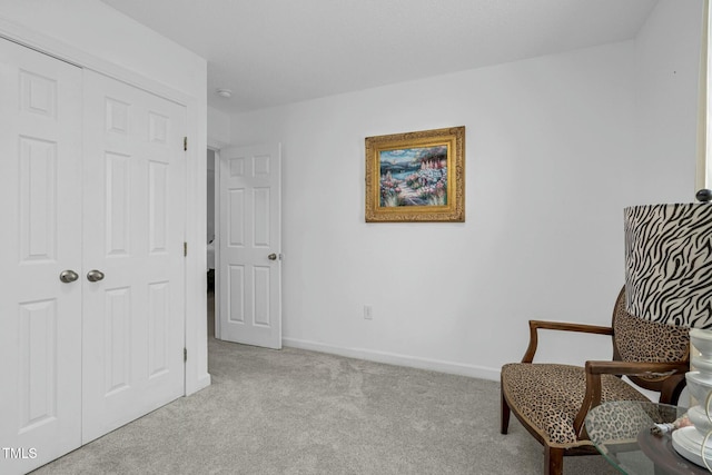 sitting room with baseboards and light colored carpet