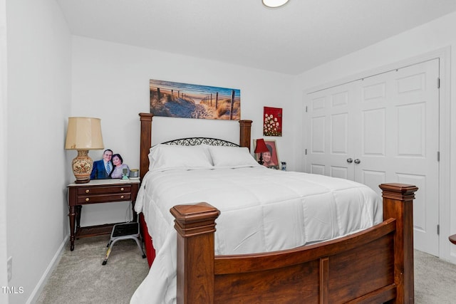 bedroom with a closet, light colored carpet, and baseboards