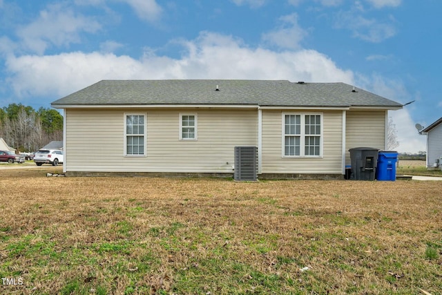 rear view of property featuring cooling unit and a lawn