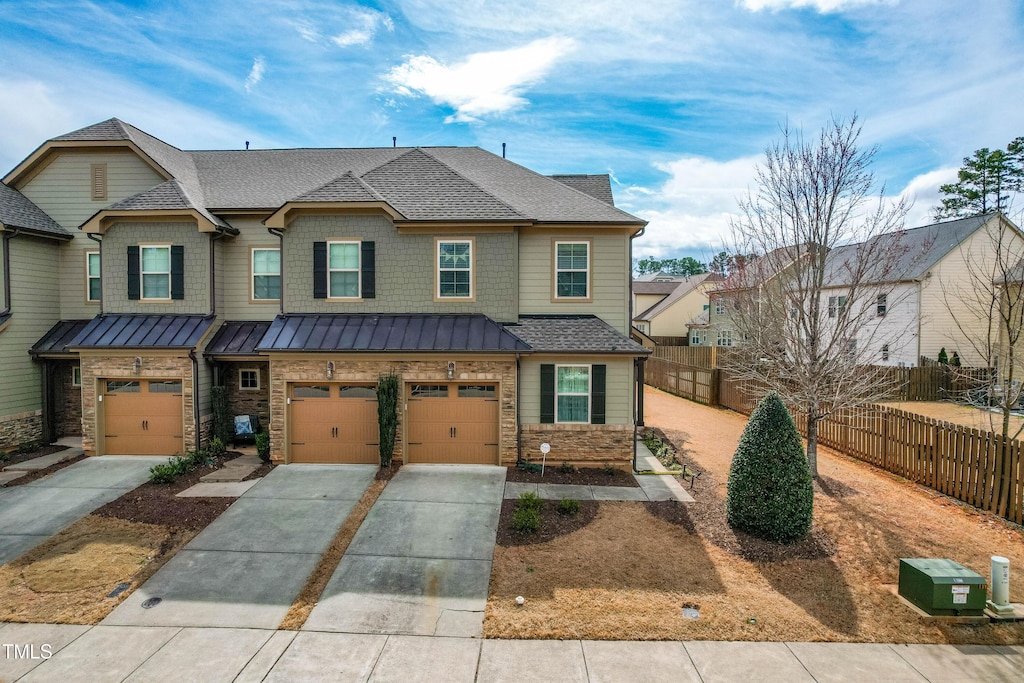 view of property with driveway, a shingled roof, metal roof, a standing seam roof, and fence