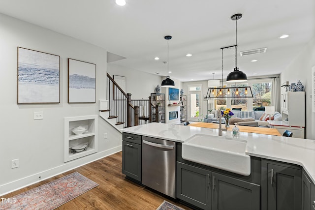 kitchen featuring a sink, visible vents, open floor plan, stainless steel dishwasher, and decorative light fixtures