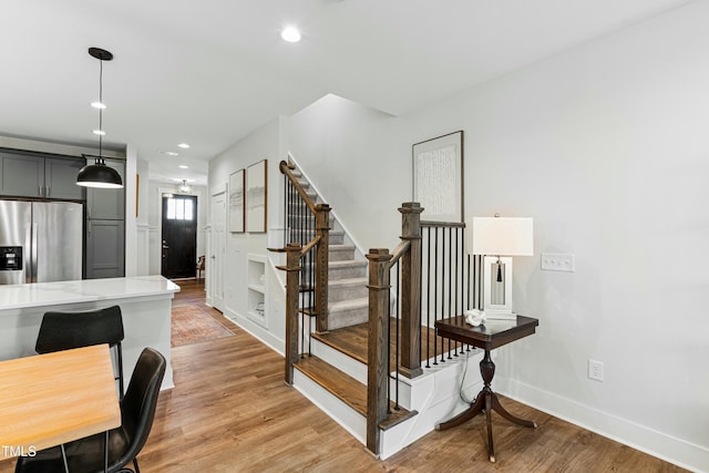 stairway with baseboards, wood finished floors, and recessed lighting