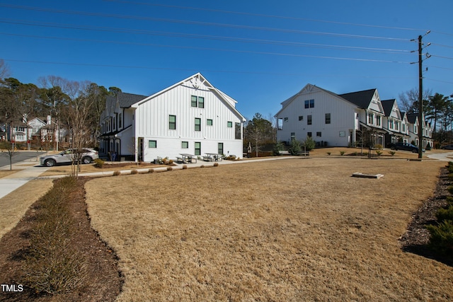 view of property exterior featuring a yard, board and batten siding, and a residential view