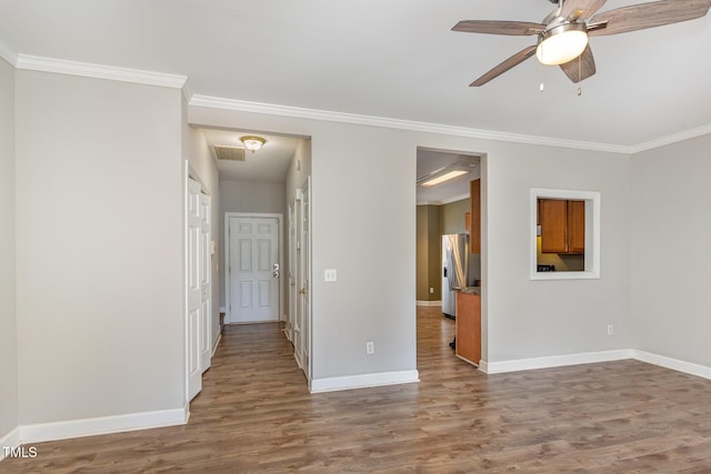 spare room with visible vents, crown molding, baseboards, and wood finished floors