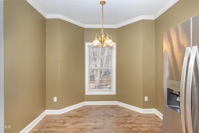 unfurnished dining area featuring crown molding, light wood-style flooring, baseboards, and an inviting chandelier