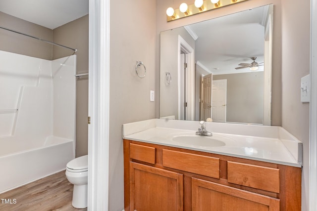 full bath featuring toilet, a ceiling fan, vanity, wood finished floors, and  shower combination