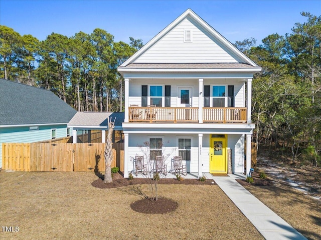 view of front of home with covered porch, fence, and a balcony