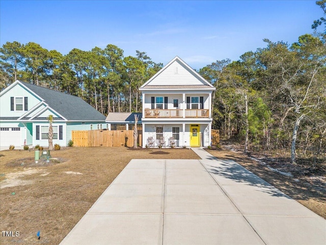 view of front of property featuring a balcony, covered porch, fence, and concrete driveway