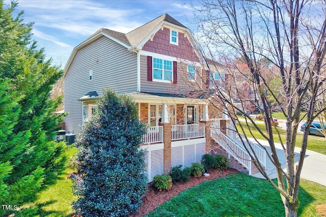 view of front of home featuring a front yard, stairway, cooling unit, a porch, and a shingled roof