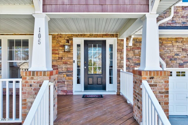 entrance to property featuring brick siding, a porch, and a garage