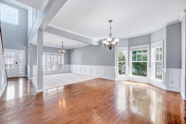 interior space featuring a wainscoted wall, wood-type flooring, and a notable chandelier