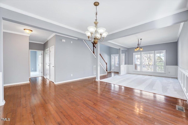 unfurnished living room featuring hardwood / wood-style flooring, stairway, visible vents, and a chandelier