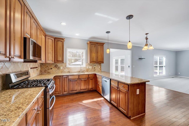 kitchen featuring a peninsula, brown cabinets, tasteful backsplash, and stainless steel appliances