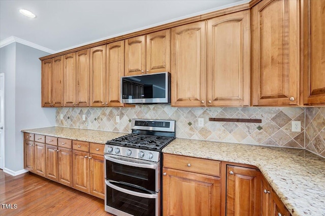 kitchen featuring light stone counters, tasteful backsplash, appliances with stainless steel finishes, and crown molding