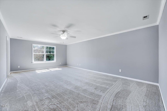 carpeted empty room with visible vents, baseboards, a ceiling fan, and crown molding