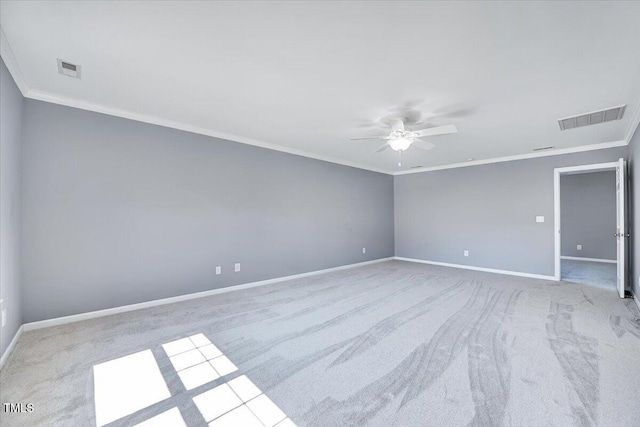 carpeted spare room featuring crown molding, baseboards, and visible vents