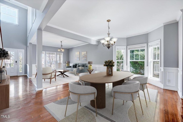 dining space with a wainscoted wall, an inviting chandelier, and wood finished floors