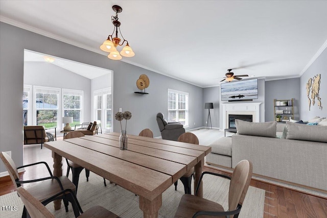 dining area featuring a glass covered fireplace, crown molding, wood finished floors, and a healthy amount of sunlight