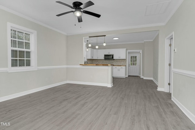 unfurnished living room with plenty of natural light, ornamental molding, light wood-type flooring, and baseboards