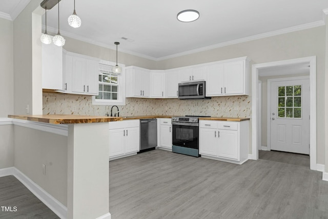 kitchen with butcher block counters, hanging light fixtures, appliances with stainless steel finishes, white cabinetry, and a peninsula