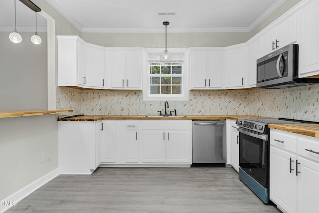 kitchen featuring stainless steel appliances, white cabinetry, hanging light fixtures, and wood counters