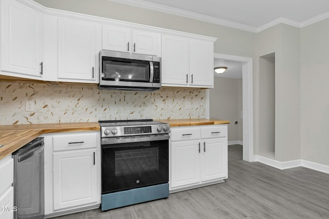 kitchen featuring stainless steel appliances, butcher block counters, backsplash, ornamental molding, and white cabinets