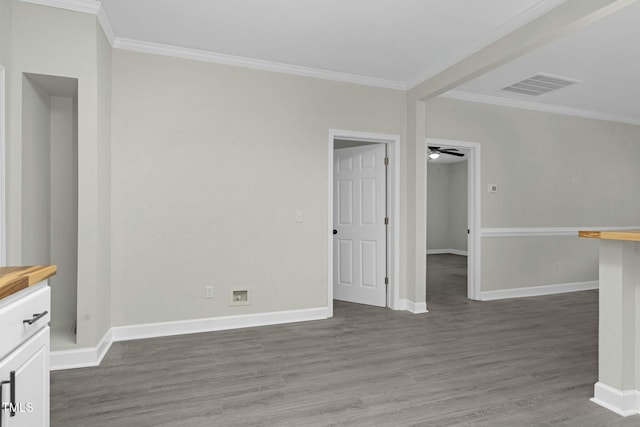 spare room featuring ornamental molding, visible vents, dark wood finished floors, and baseboards