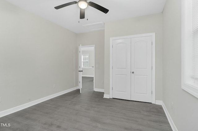 unfurnished bedroom with a closet, wood finished floors, a ceiling fan, and baseboards