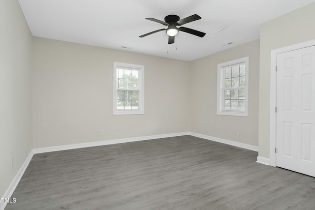 unfurnished room featuring a wealth of natural light, baseboards, and wood finished floors