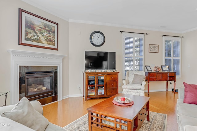 living area featuring baseboards, ornamental molding, wood finished floors, and a glass covered fireplace