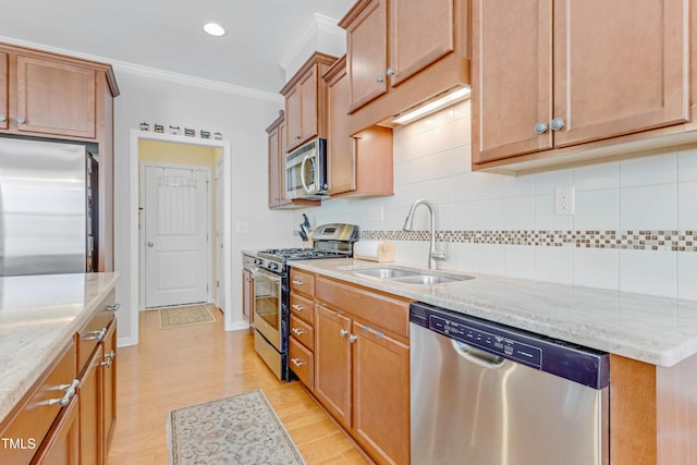 kitchen featuring light stone counters, stainless steel appliances, a sink, ornamental molding, and decorative backsplash