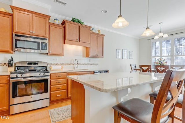 kitchen featuring stainless steel appliances, ornamental molding, a breakfast bar, and visible vents