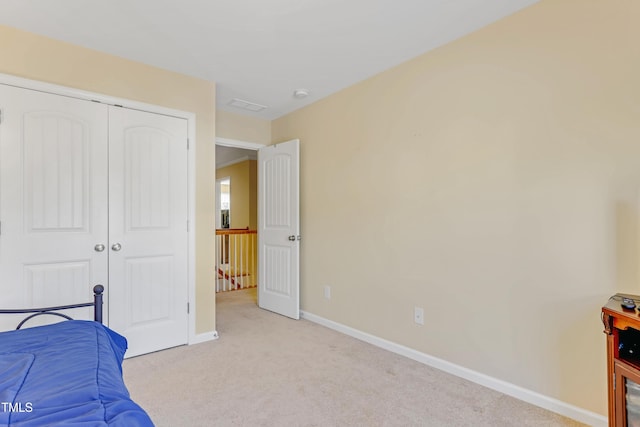 bedroom with light carpet, a closet, visible vents, and baseboards