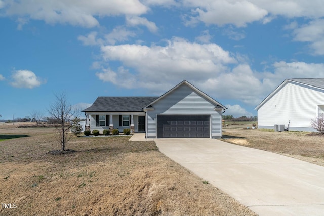 view of front of home featuring an attached garage, driveway, a front lawn, and central AC