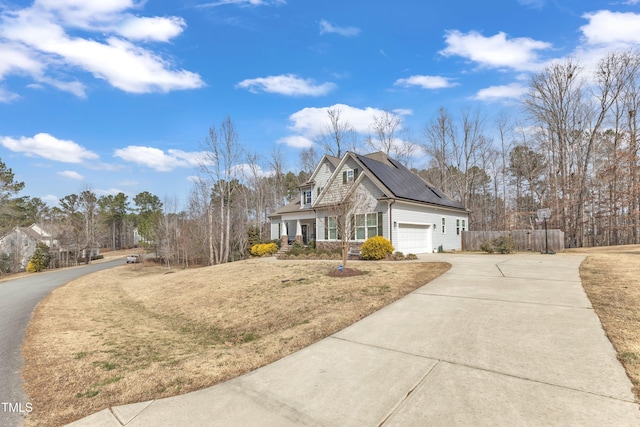 view of home's exterior featuring driveway, a garage, a lawn, fence, and roof mounted solar panels