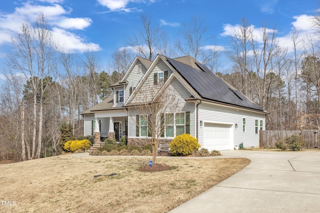 view of front facade featuring driveway, a garage, fence, roof mounted solar panels, and a front lawn