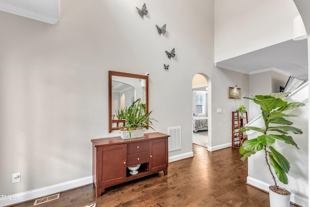 entrance foyer featuring dark wood-style floors, visible vents, and arched walkways