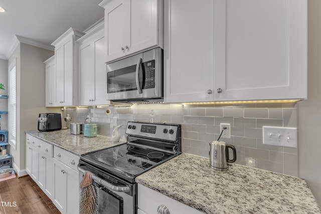 kitchen featuring stainless steel appliances, tasteful backsplash, white cabinets, and crown molding