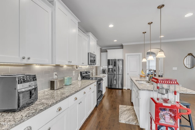 kitchen with a sink, ornamental molding, appliances with stainless steel finishes, decorative backsplash, and dark wood finished floors