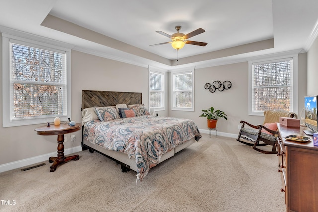 carpeted bedroom featuring visible vents, baseboards, a raised ceiling, and a ceiling fan