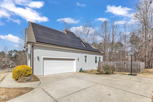 view of home's exterior featuring a garage, solar panels, a shingled roof, fence, and driveway