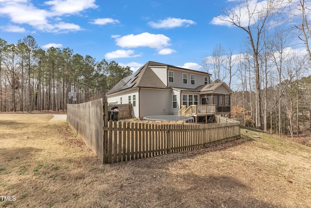 back of property featuring a sunroom, a shingled roof, fence, and a wooden deck