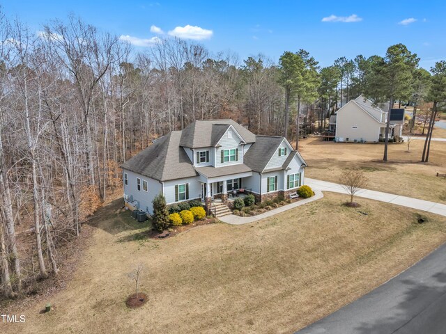 traditional home with a porch, a front yard, roof with shingles, and driveway