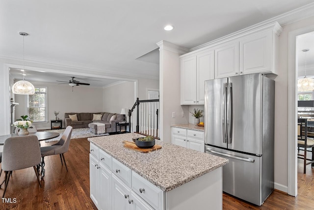 kitchen featuring white cabinets, a kitchen island, dark wood-type flooring, freestanding refrigerator, and crown molding