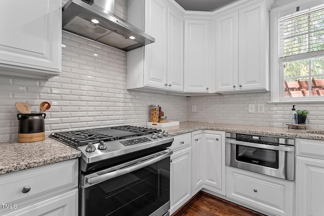 kitchen featuring stainless steel appliances, white cabinets, backsplash, and wall chimney exhaust hood