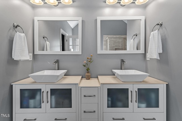 full bath featuring a shower, a sink, and double vanity